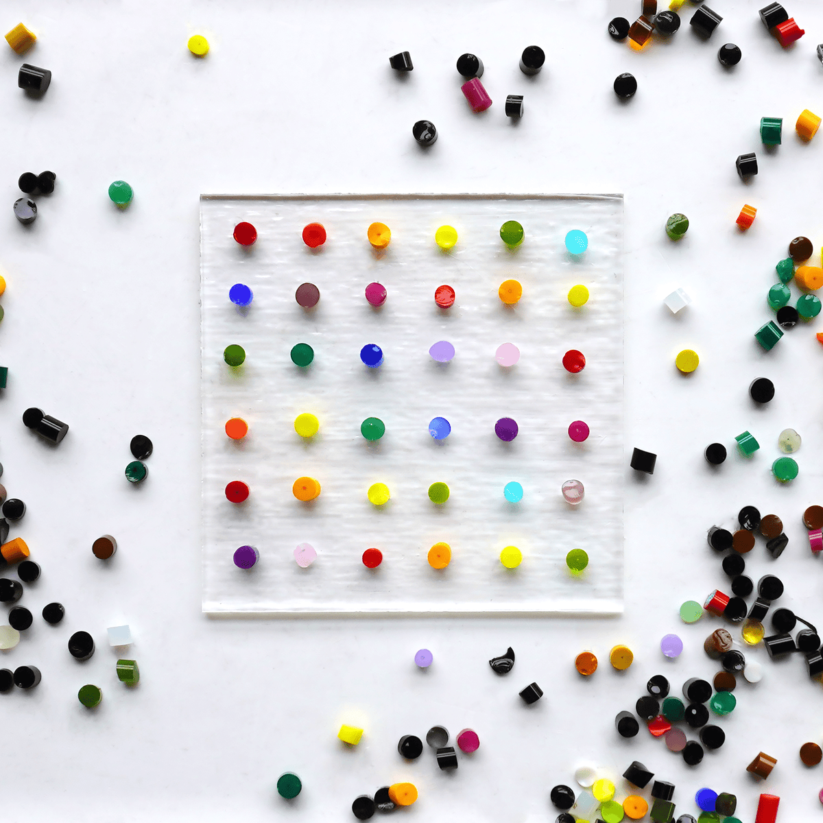 Colorful glass dots arranged in a grid pattern on a white background