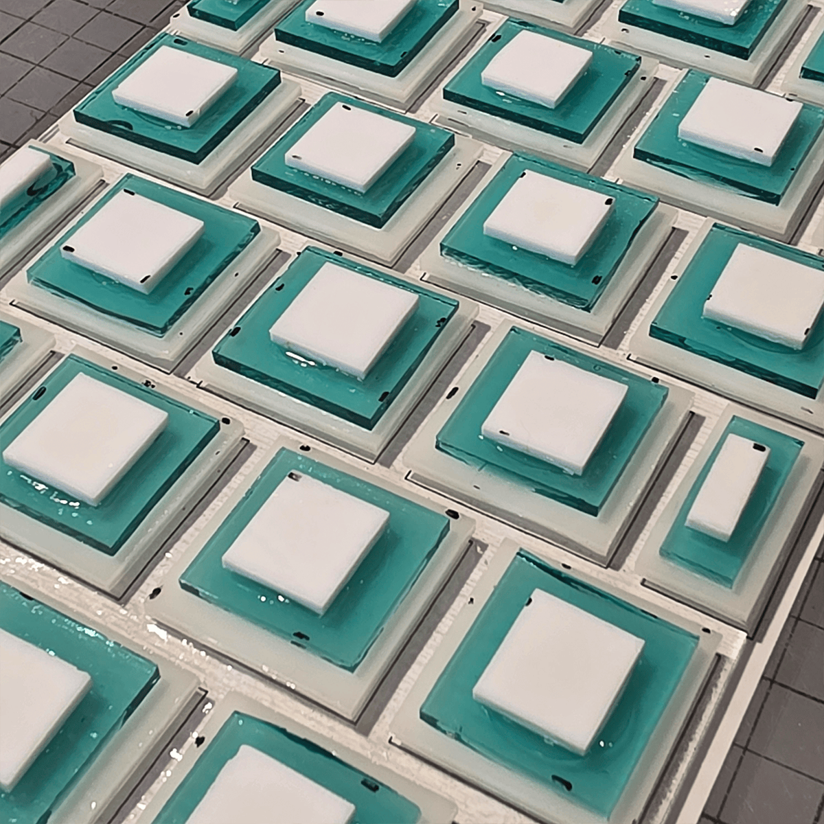 Close-up of a grid of white and turquoise glass squares stacked on top of each other